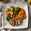Apple roasted pork tenderloin dinner with mashed sweet potatoes and mixed vegetables.