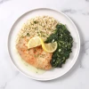 Prepared lemon tilapia meal with flaky fish, brown rice, and garlicky sautéed spinach.