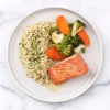 Prepared seared salmon dinner with brown butter sauce, brown rice, and roasted vegetables.