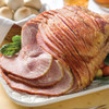 Fully cooked artisan spiral sliced bone-in ham glazed with Vermont maple syrup on a serving platter