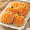Pumpkin-shaped sugar cookies with orange frosting and green icing stems on a white platter