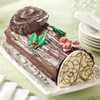 Chocolate yule log cake on a white platter with holly decorations and red-and-white icing mushrooms