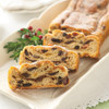 Sliced fruit stollen with visible raisins and candied fruit on a white platter beside the remaining loaf