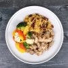 Top-down view of jerk chicken with coconut rice and beans and vegetables