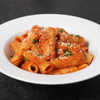 Rigatoni with Italian sausage and cherry pepper marinara topped with Parmesan on a white plate