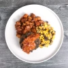 Top-down view of BBQ bacon and onion jam burger with potatoes and corn salad