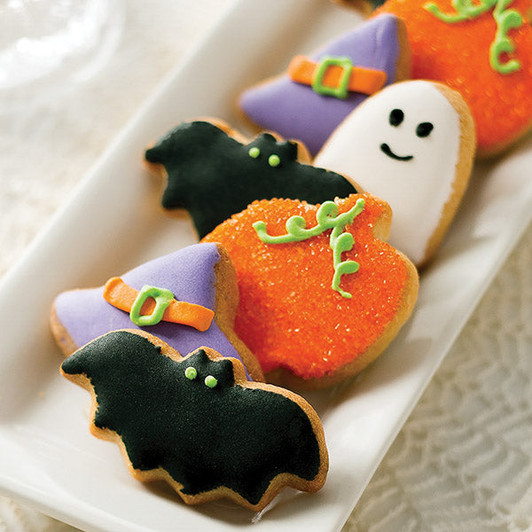 Spookies Halloween sugar cookies decorated as black bats, white ghosts, orange pumpkins, and purple witch hats