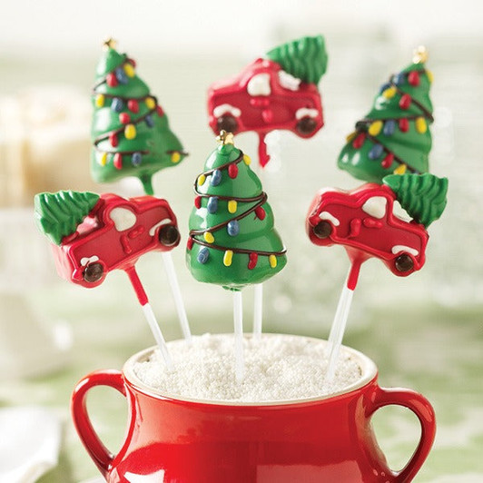 Christmas tree and red truck cake pops arranged upright in a red mug with white decorative filling