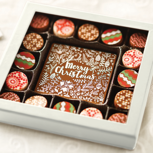 Holiday truffles in a white gift box around a milk chocolate card reading Merry Christmas.