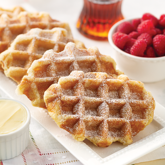 Belgian pearl sugar waffles on a white plate with butter and berries shown as serving suggestions.