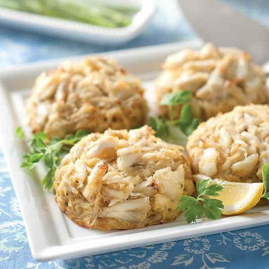 Colossal Crab Cakes topped with large pieces of crab and served with lemon; the order contains six 6 oz cakes.