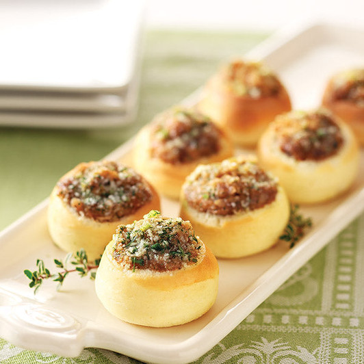 Mini bread boules filled with browned cheese and onions, arranged on a serving platter; eighteen pieces per order.