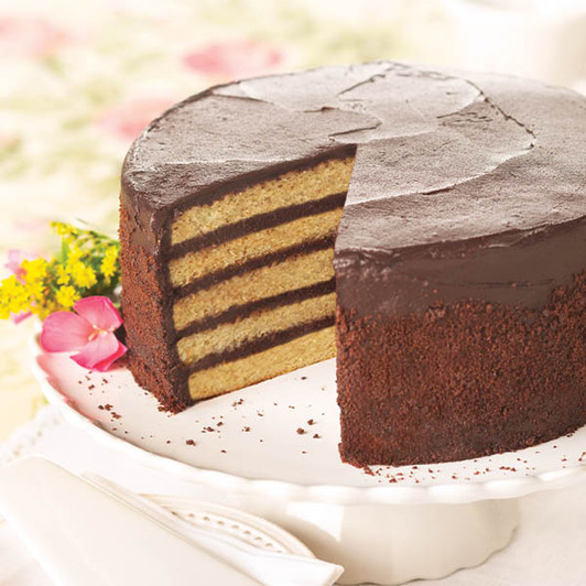 Smith Island Cake with a slice removed, showing alternating yellow cake layers and chocolate fudge icing.
