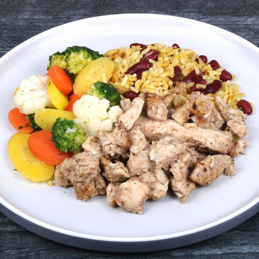 Jerk chicken with coconut rice, red beans, cauliflower, carrots, and broccoli on a white plate