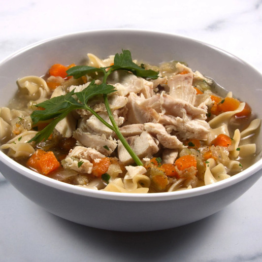 Bowl of classic chicken noodle soup with chicken, egg noodles, carrots, and parsley