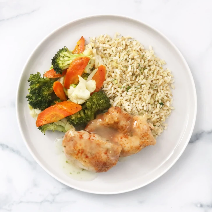 Roasted chicken thigh with savory chicken jus, brown rice, and mixed vegetables.