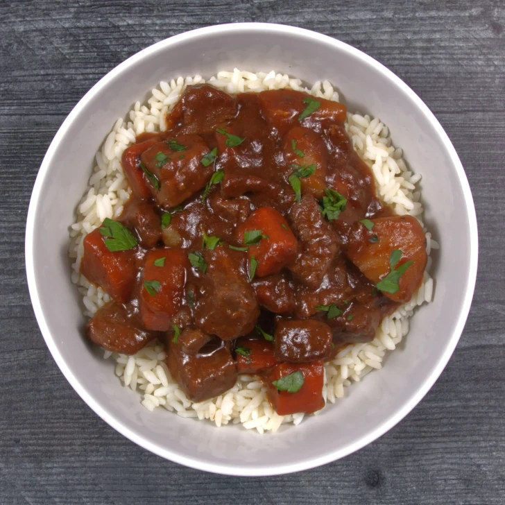 Prepared beef stew with Bourguignon sauce, vegetables, and white rice.