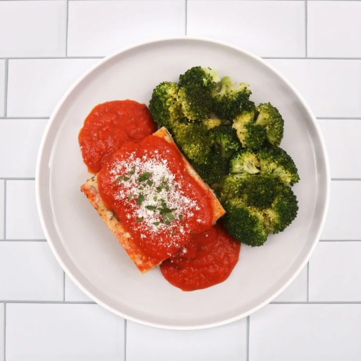 Cheesy vegetable lasagna dinner served with seasoned roasted broccoli.