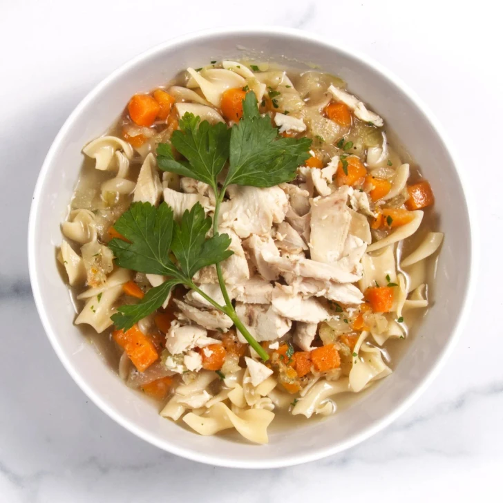 Top-down view of classic chicken noodle soup in a white bowl