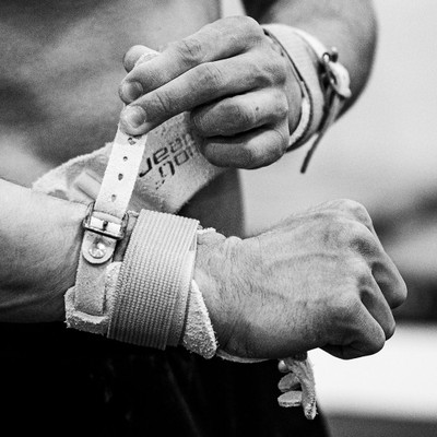 Athlete tightening buckle on Wolf Wear ALPHA Combo Fastener High Bar Grips
