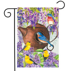 Briarwood Lane spring garden flag with colorful birds, teapot birdhouse, and purple flowers on display.