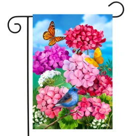 Briarwood Lane garden flag with pink geraniums, blue jay, butterflies, and colorful spring flowers.