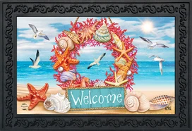 Briarwood Lane Coral Wreath Doormat with seashells and starfish on a beach background welcomes guests.