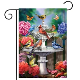 Spring Bath Birds Garden Flag with colorful birds, flowers, and butterflies around a white birdbath.