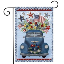 Blue vintage pickup truck with USA license plate and patriotic flowers on Celebrate America garden flag.