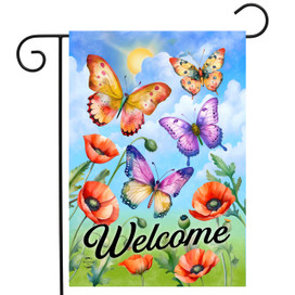 Colorful garden flag with butterflies, poppies, and "Welcome" text on blue sky background with clouds.