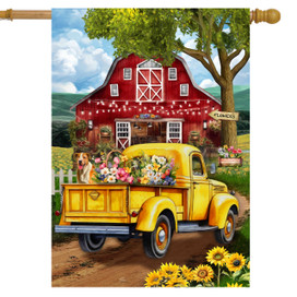 Yellow vintage truck with flowers and dog, parked in front of red barn house flag.