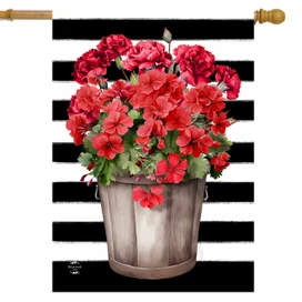 Striped house flag with red geraniums in a wooden bucket on black and white stripes background.
