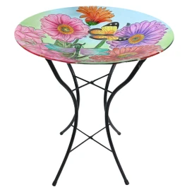 Round glass birdbath with colorful zinnias and butterfly design on black metal stand base.