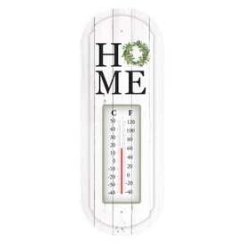 Home metal thermometer with temperature gauge and green wreath on white wooden background with HOME text.