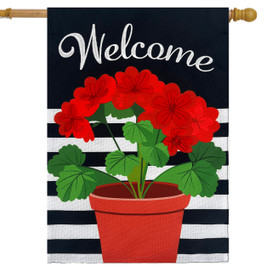 Red geraniums in red pot on black and white striped house flag with welcome text.