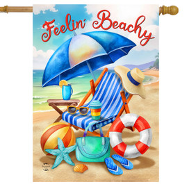 Feelin Beachy house flag with beach chair, umbrella, and accessories on sandy beach background.