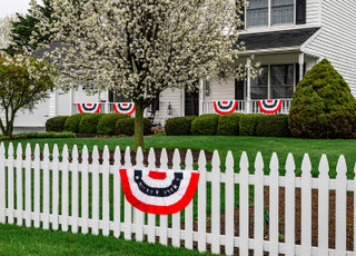 Briarwood Lane Patriotic Bunting on a white picket fence with American flag colors USA decoration.