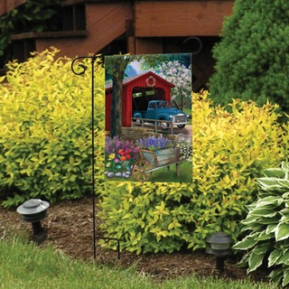 Briarwood Lane small printed garden flag with colorful spring scene of a covered bridge and flowerbed.