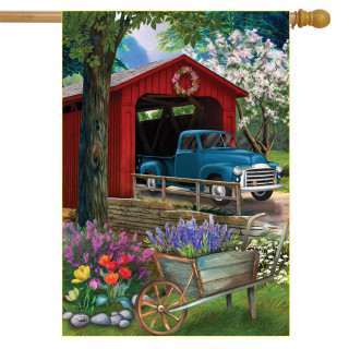 Briarwood Lane spring house flag with colorful covered bridge, truck, and vibrant springtime flower display.