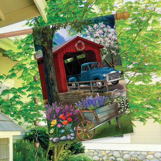 Briarwood Lane Bridge in Blooms Spring House Flag with colorful, printed, covered bridge design on porch.