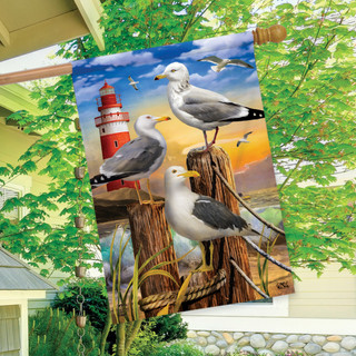 Briarwood Lane Seagulls Summer House Flag with lighthouse and coastal design on a backyard porch display.