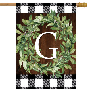 Briarwood Lane monogrammed house flag with greenery wreath and checkered border on a wooden background.