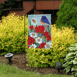 Briarwood Lane Spring Friendship Garden Flag with blue bird, red flowers, and white daisies displayed outdoors.