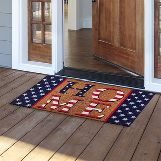 Briarwood Lane American Home Coir Welcome doormat with American flag design on wooden porch outside doorway.