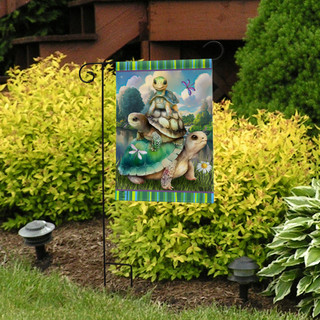 Briarwood Lane Turtle Trio Garden Flag with colorful turtle design on green background outdoors.