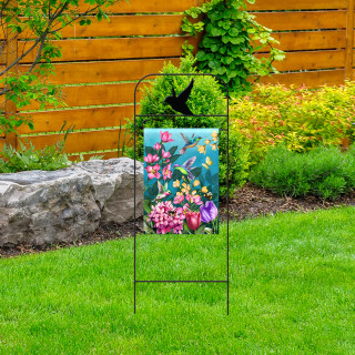 Briarwood Lane wrought iron hummingbird garden flag arbor with colorful floral design on green lawn outdoors.