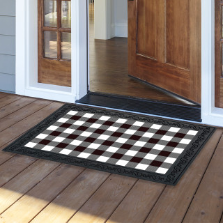 Black and white check doormat on wooden porch outside open door with decorative border.