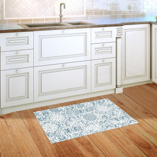Blue and white ornamental doormat on wooden floor in front of kitchen sink and cabinets.