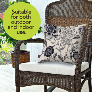 Woodcut Floral Burlap Pillow on wicker chair with white cushion and floral design.
