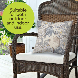 Vintage patchwork burlap pillow on wicker chair with white cushion and blue, beige pattern.